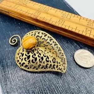 Vintage gold filigree leaf brooch with tigers eye gemstone cabochon Vintage gold filigree leaf brooch with tigers eye gemstone cabochon